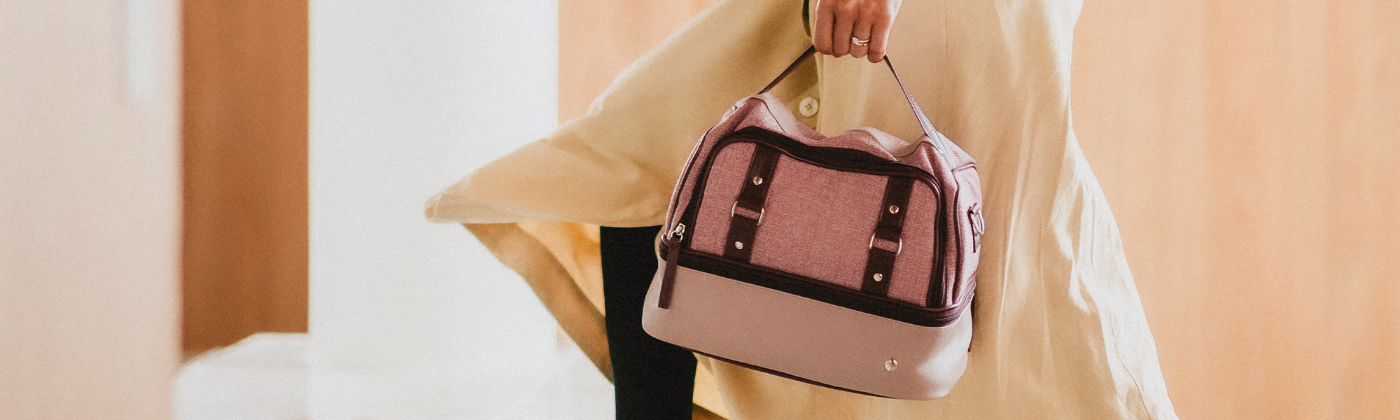 Mulher caminhando e segurando uma bolsa térmica vermont da PACCO de duas cores nos tons de rosa e vinho.