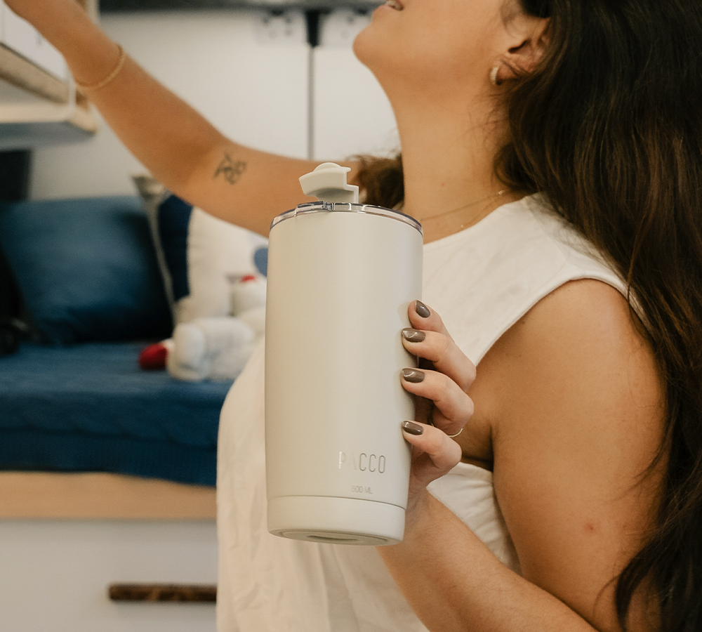 Copo térmico ThermoCup da PACCO na cor creme sendo segurado por uma mulher, ideal para o dia a dia.