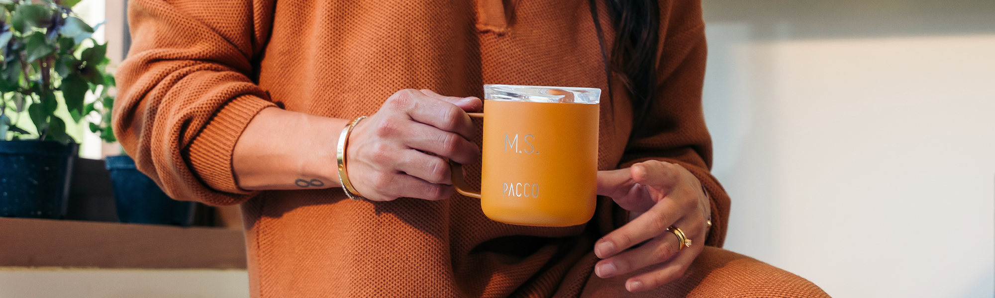 Pessoa segurando a caneca térmica Fokus da PACCO na cor caramelo, perfeita para um momento de foco no trabalho ou estudos.